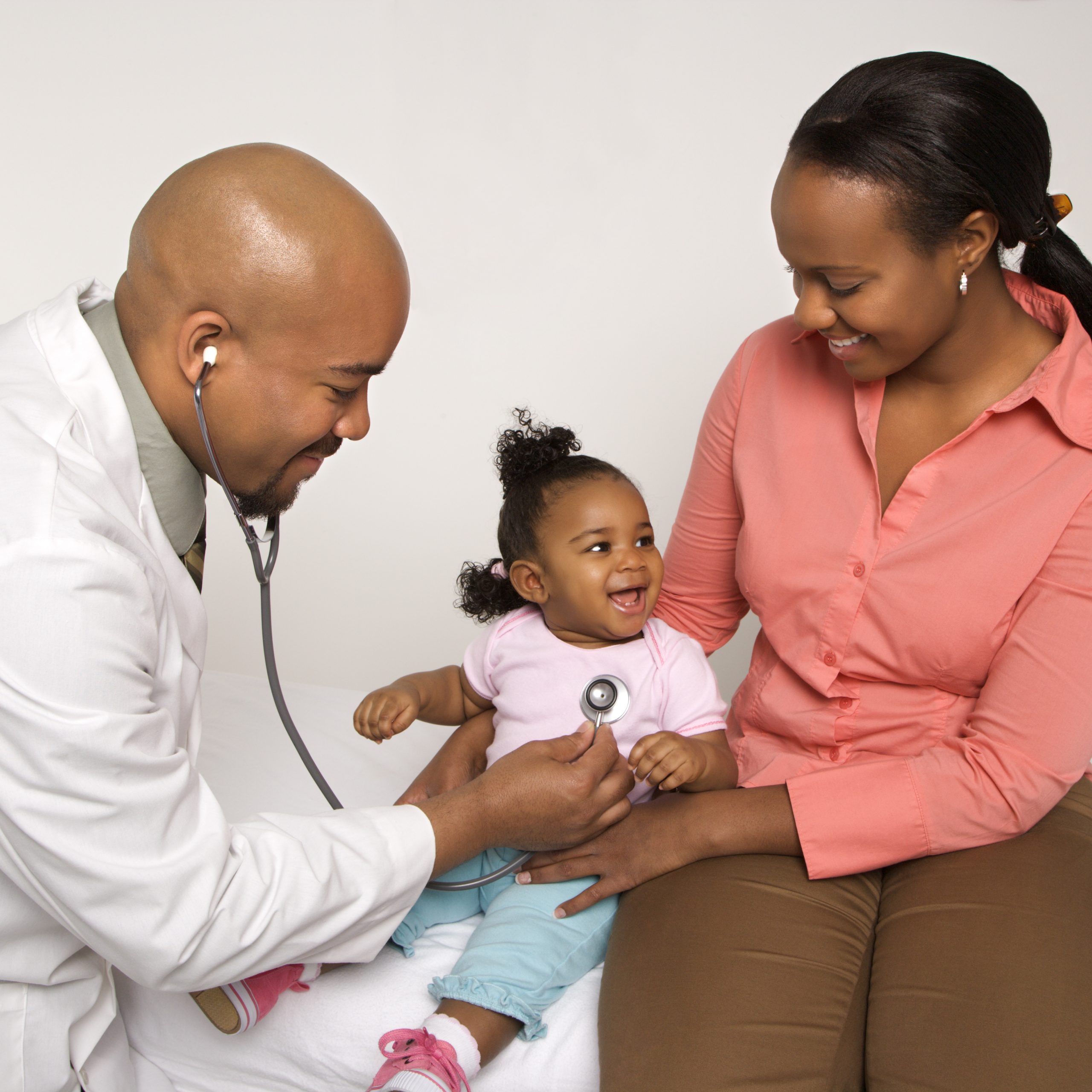 Mother holding baby for pediatrician to examine.